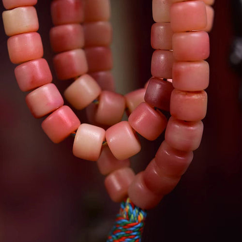 Close up of natural camel bone mala beads with reddish half-blood pattern and earthy texture