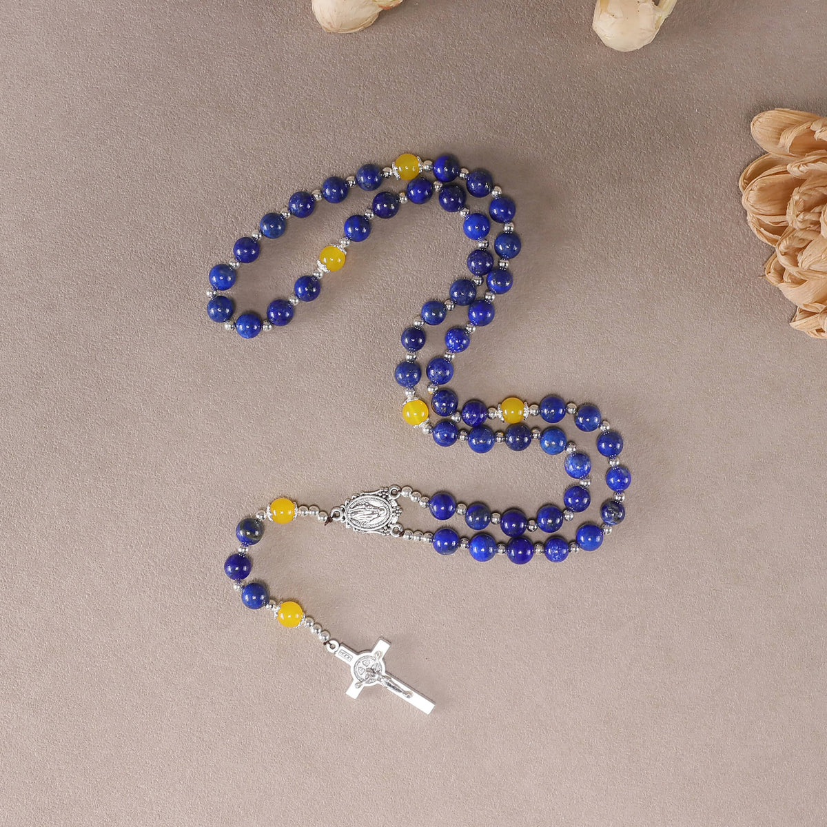 Flat lay view of 8mm natural lapis lazuli catholic rosary, yellow agate accent beads with antique silver medal and crucifix