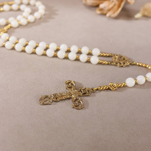 Closeup of vintage gold ornate crucifix on natural white plant seed handmade rosary